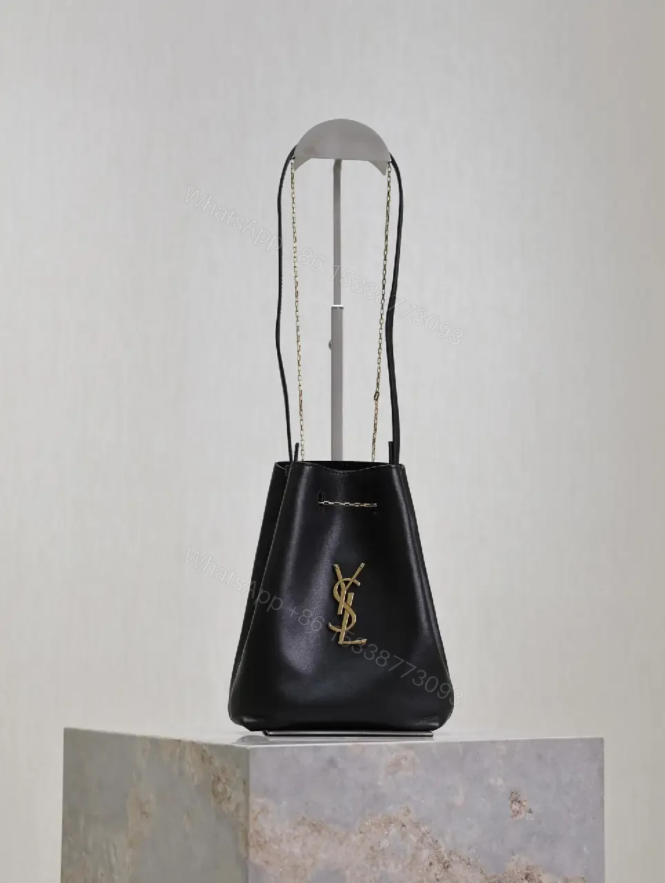 View 9 of Black leather bucket bag with gold-tone YSL monogram and chain straps for everyday luxury