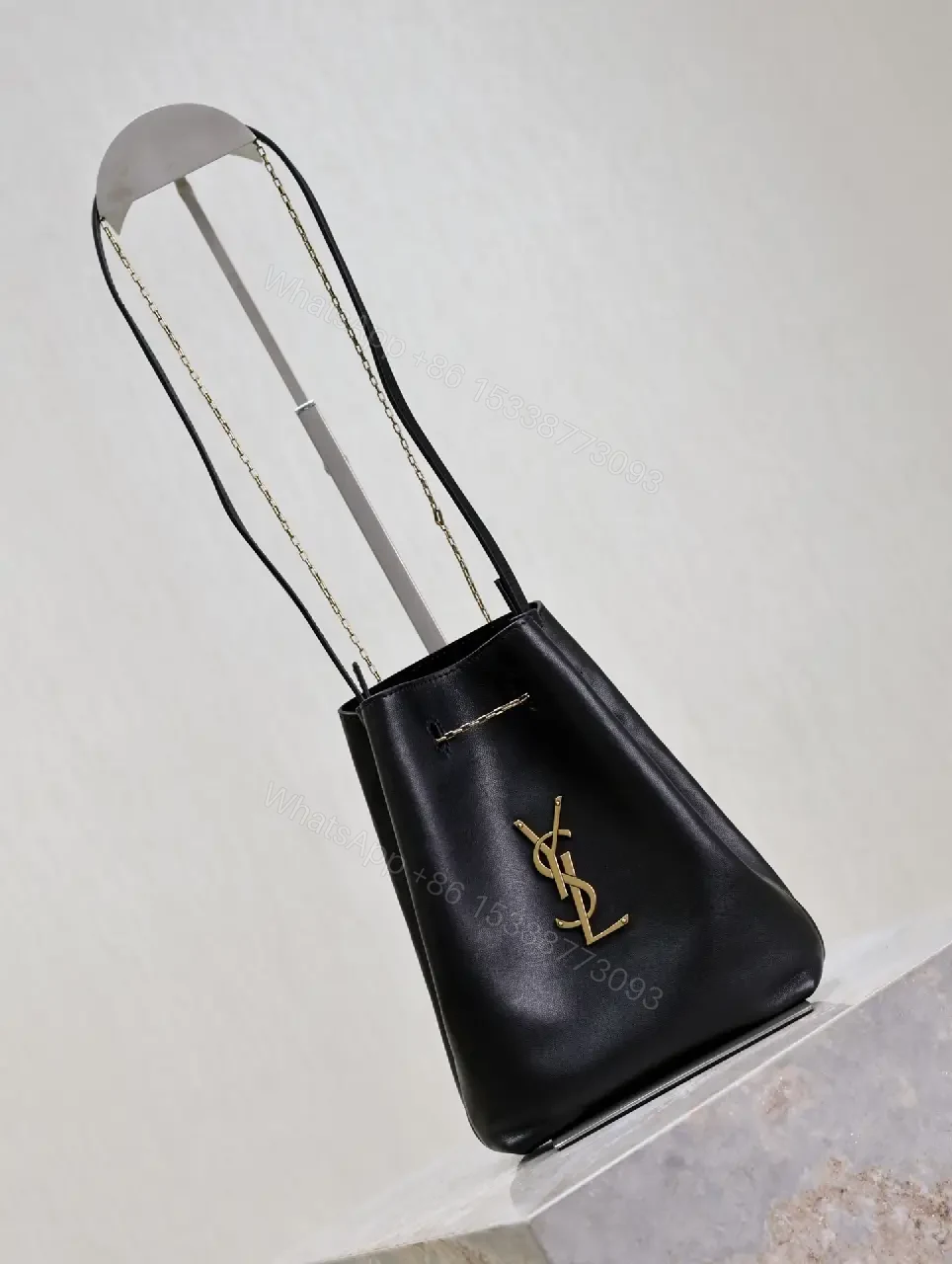 View 4 of Black leather bucket bag with gold-tone YSL monogram and chain straps for everyday luxury