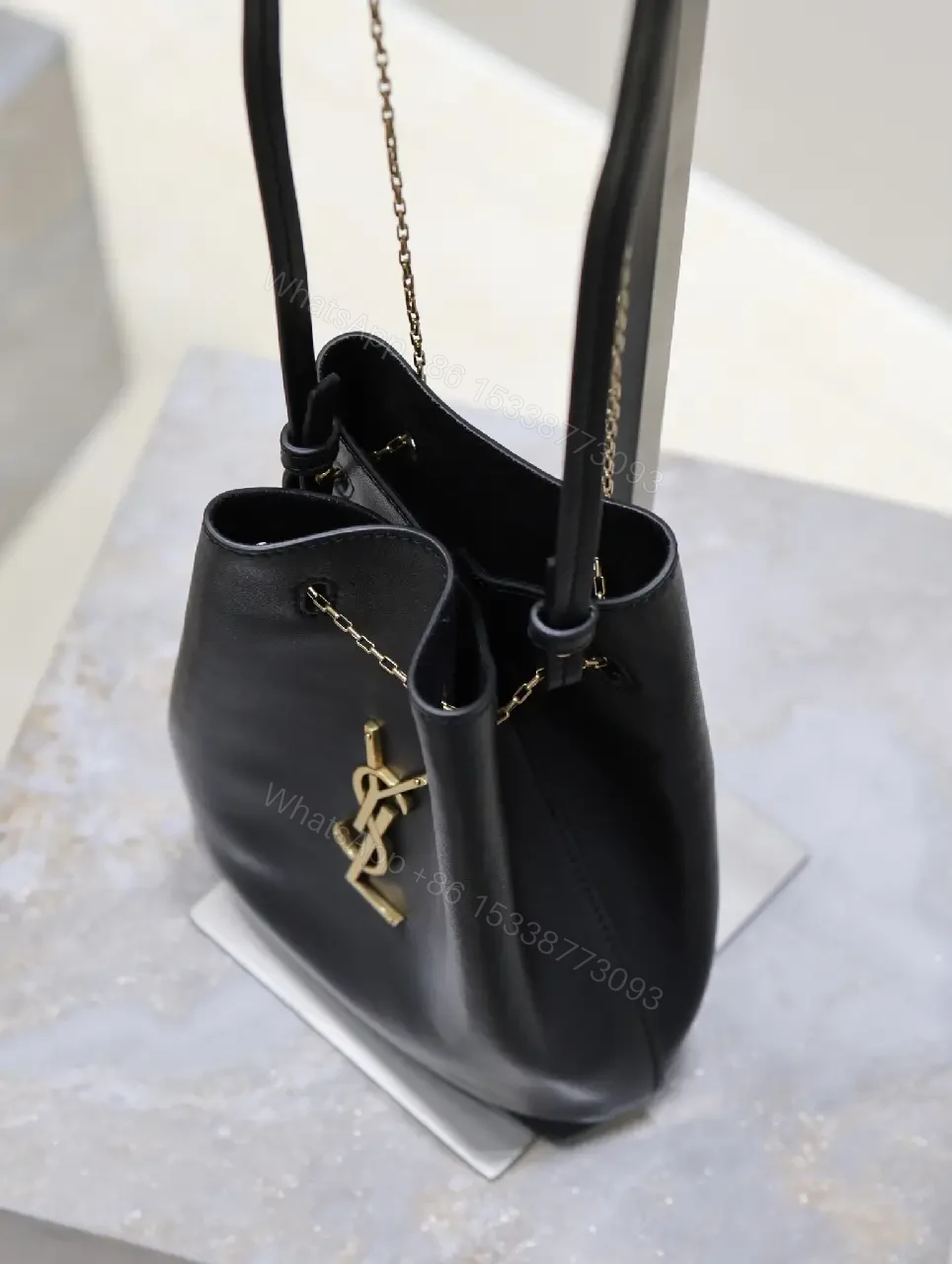 View 7 of Black leather bucket bag with gold-tone YSL monogram and chain straps for everyday luxury