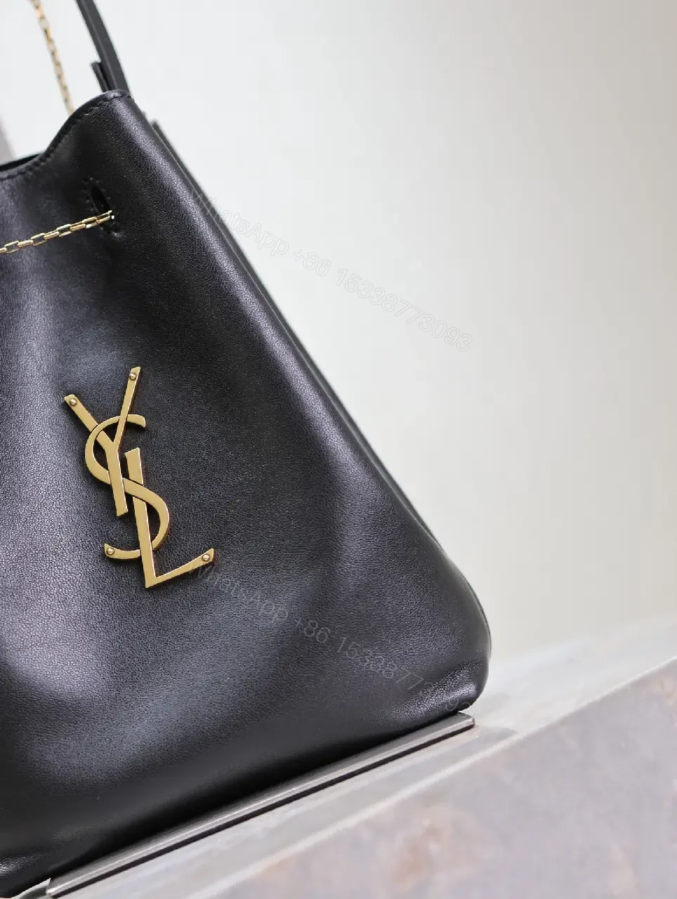 View 6 of Black leather bucket bag with gold-tone YSL monogram and chain straps for everyday luxury