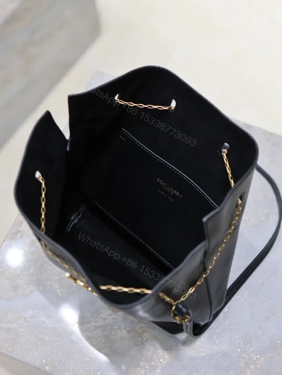View 8 of Black leather bucket bag with gold-tone YSL monogram and chain straps for everyday luxury
