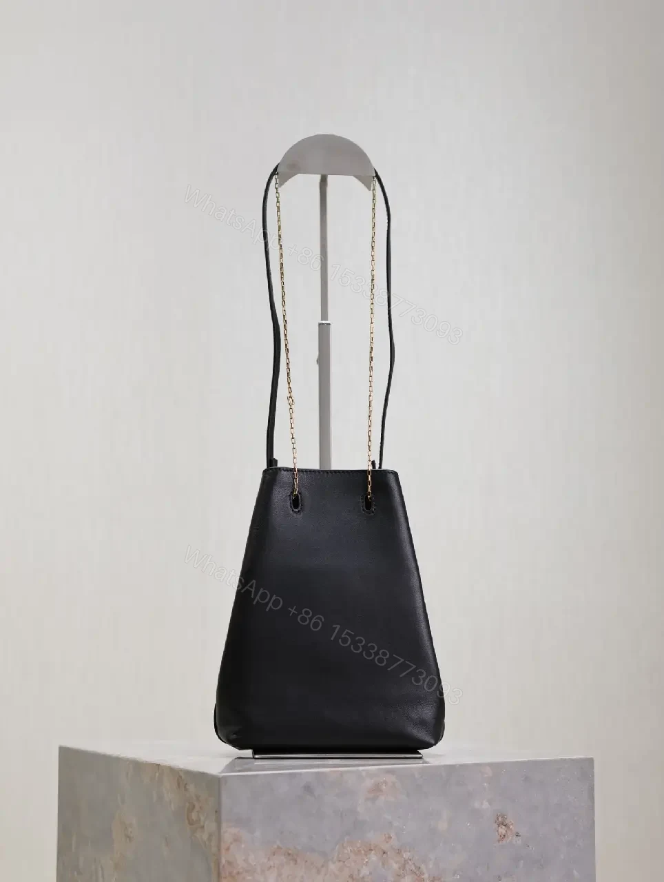 View 2 of Black leather bucket bag with gold-tone YSL monogram and chain straps for everyday luxury
